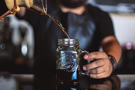 Coffee being poured into a heat resistant mason jar.